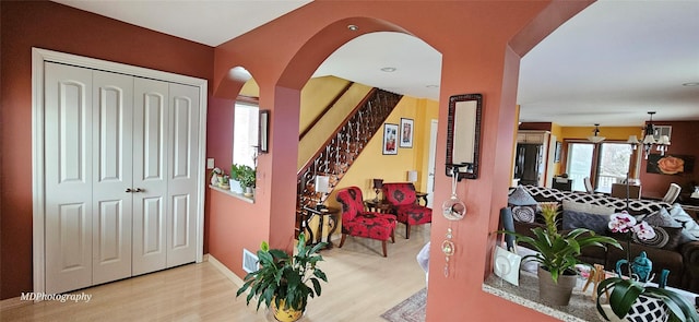 foyer entrance featuring a notable chandelier, arched walkways, baseboards, wood finished floors, and visible vents