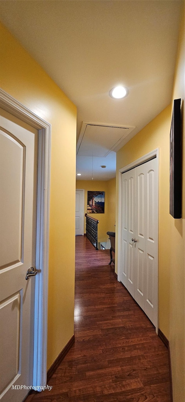 hallway featuring recessed lighting, baseboards, attic access, and dark wood-type flooring