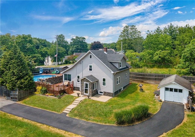 exterior space with an outdoor structure, a front lawn, fence, stone siding, and a detached garage