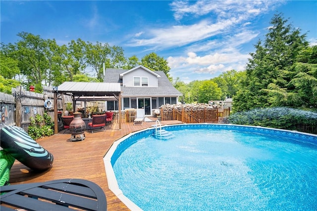 view of pool featuring a fenced in pool, a sunroom, a fenced backyard, and a deck