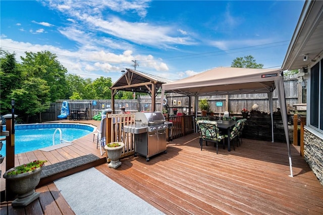 view of swimming pool with a gazebo, a deck, a fenced in pool, outdoor dining area, and a grill