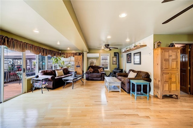 living area with a ceiling fan, decorative columns, a wall unit AC, and light wood-type flooring