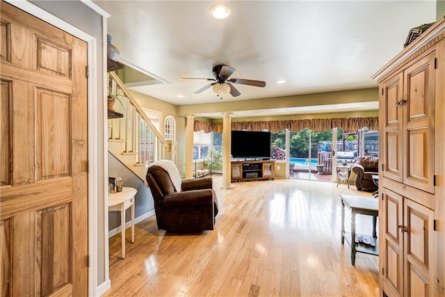 living area featuring a ceiling fan, stairway, baseboards, light wood finished floors, and recessed lighting