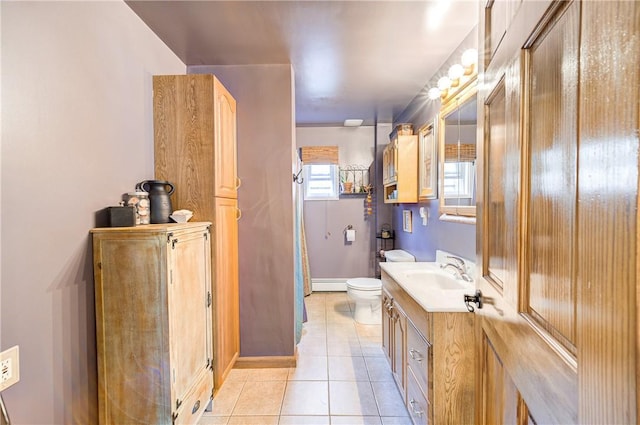 bathroom with vanity, toilet, baseboards, baseboard heating, and tile patterned floors