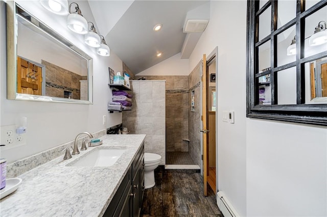 full bath featuring vaulted ceiling, a tile shower, toilet, and wood finished floors