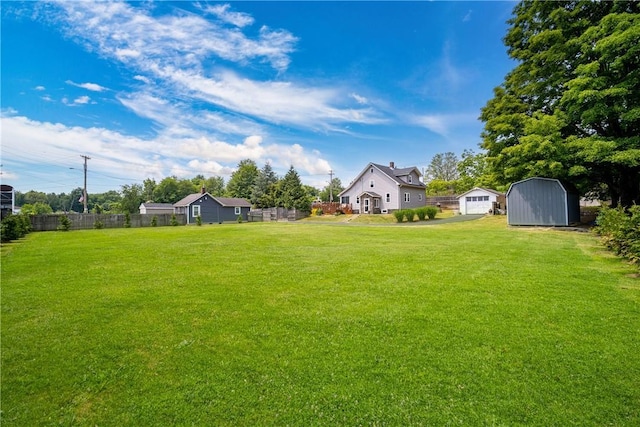 view of yard featuring an outbuilding, a shed, fence, and a detached garage