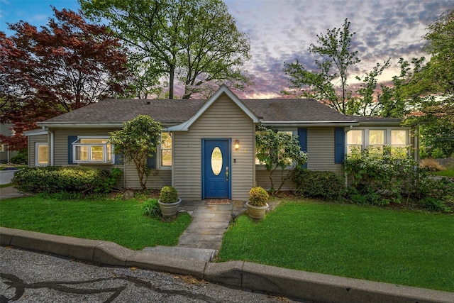 view of front of home with a lawn and roof with shingles