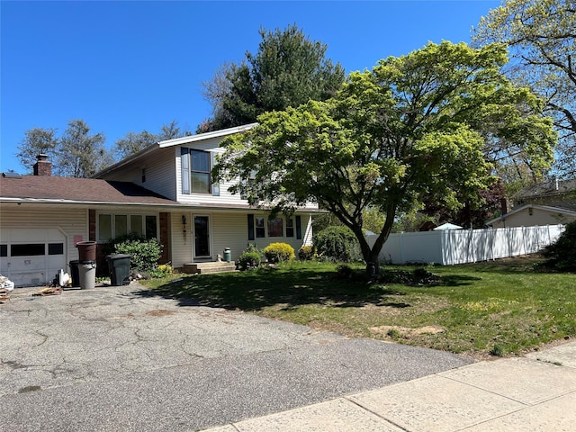 view of front of home with a garage, a front lawn, aphalt driveway, fence, and a chimney
