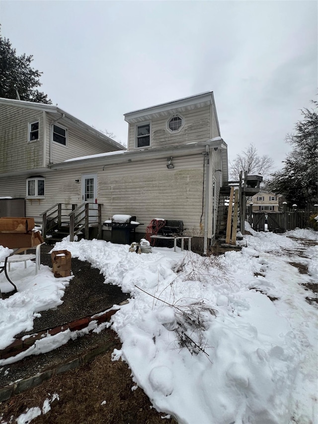 snow covered property featuring fence and a wooden deck
