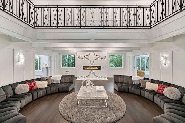 living room with a premium fireplace, wood finished floors, and a towering ceiling
