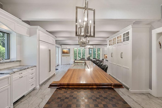 dining area with an inviting chandelier, beam ceiling, and marble finish floor