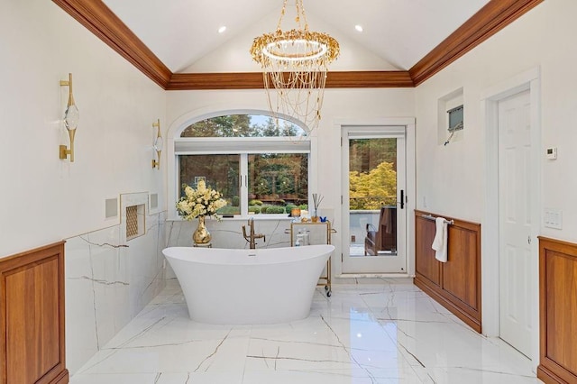 full bath featuring a freestanding tub, wainscoting, marble finish floor, a notable chandelier, and lofted ceiling