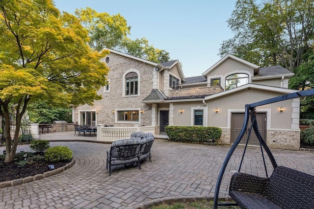 back of house with stone siding, a patio area, and stucco siding