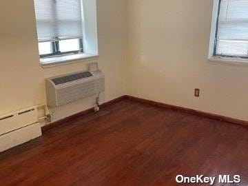 25-54 12th St Unit 3D, Long Island City, NY 11102 - unfurnished room with an AC wall unit, dark wood-style flooring, and baseboards