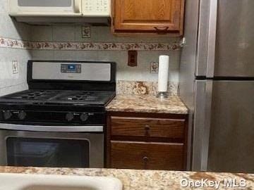 25-54 12th St Unit 3D, Long Island City, NY 11102 - kitchen with brown cabinets, stainless steel appliances, and light stone counters