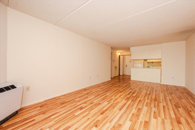 unfurnished living room with radiator and light wood-style floors