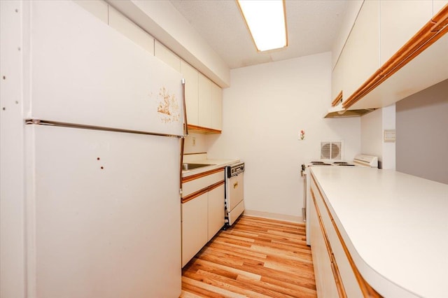 kitchen with white appliances, light wood finished floors, and light countertops