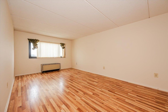 unfurnished room with radiator heating unit and light wood-style flooring