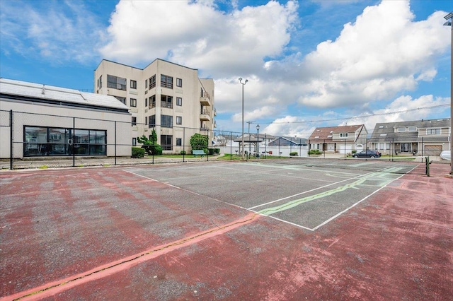 view of property's community with a tennis court, fence, and uncovered parking