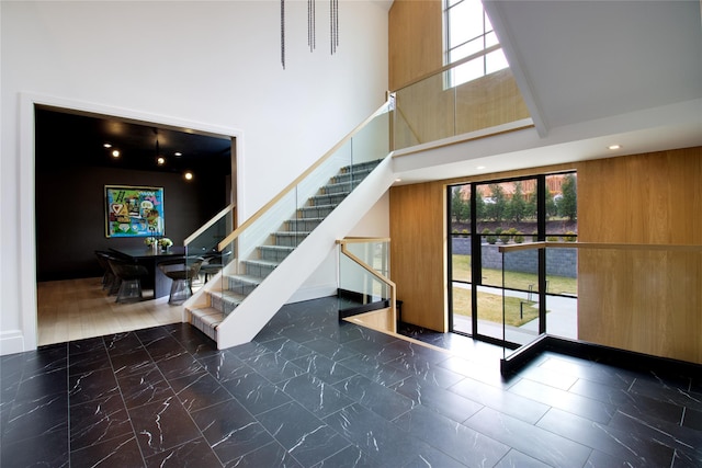 stairs with a healthy amount of sunlight, marble finish floor, and a towering ceiling