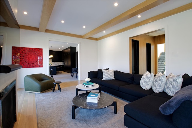 living area with a high end fireplace, baseboards, beamed ceiling, light wood-style floors, and recessed lighting
