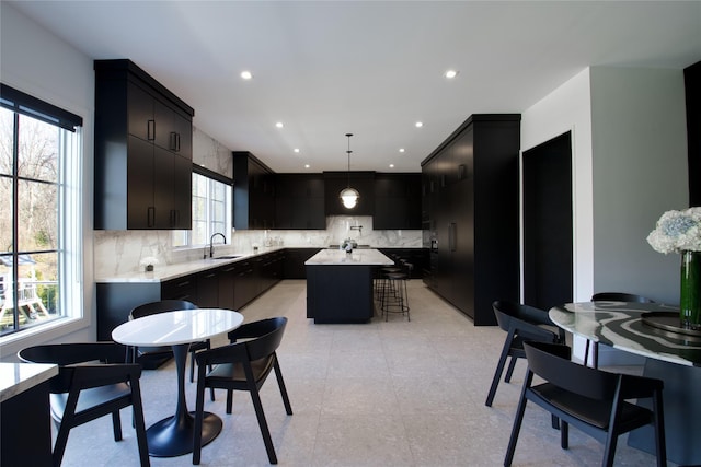 kitchen with dark cabinets, decorative backsplash, a kitchen island, and light countertops