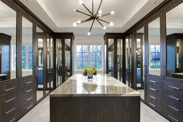 walk in closet with a tray ceiling and a chandelier