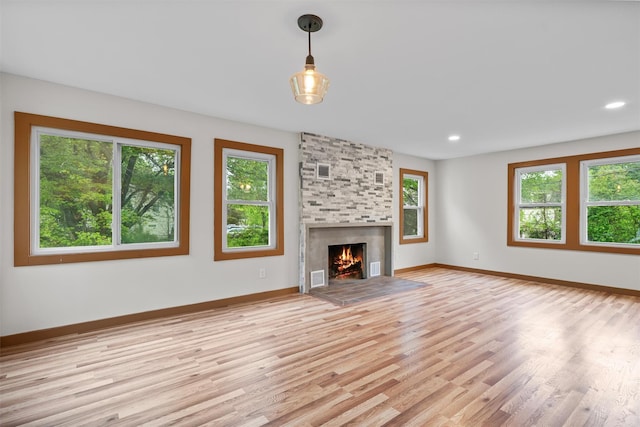 unfurnished living room with light wood-style flooring, a fireplace, baseboards, and recessed lighting