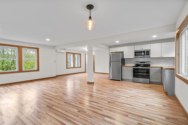 kitchen featuring appliances with stainless steel finishes, a wall mounted AC, plenty of natural light, light countertops, and recessed lighting