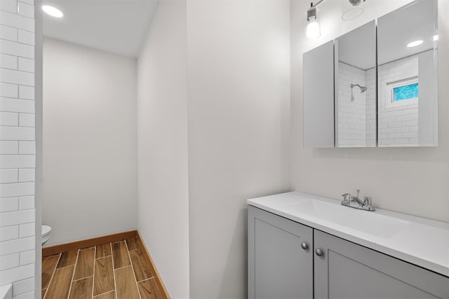 full bath with wood finish floors, toilet, a shower, vanity, and baseboards