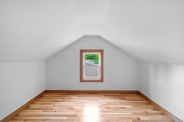 additional living space featuring vaulted ceiling, light wood-style flooring, and baseboards