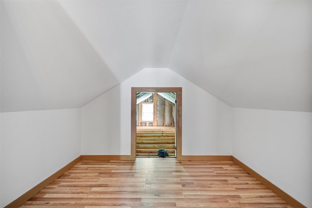 bonus room featuring light wood-style flooring, lofted ceiling, and baseboards