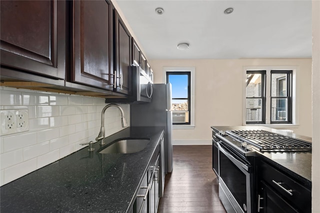 kitchen featuring decorative backsplash, a sink, baseboards, stainless steel appliances, and dark wood-type flooring