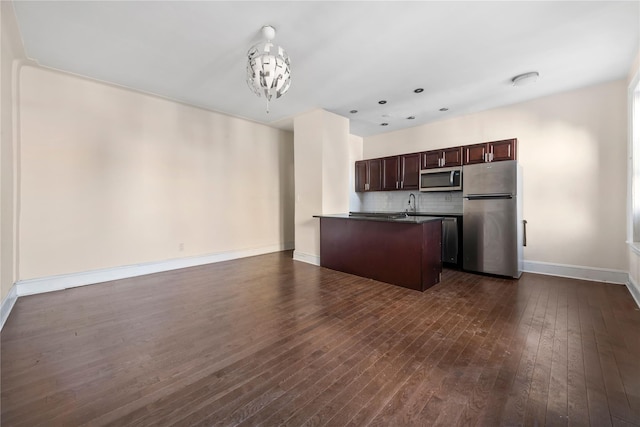 kitchen with dark brown cabinets, dark countertops, stainless steel appliances, open floor plan, and dark wood-style floors