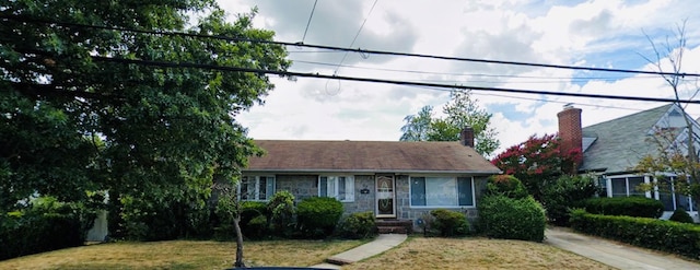 view of front facade with a chimney, a front yard, and stone siding