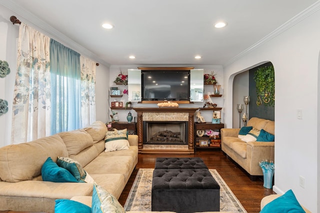 living area featuring ornamental molding, wood finished floors, a fireplace, recessed lighting, and arched walkways