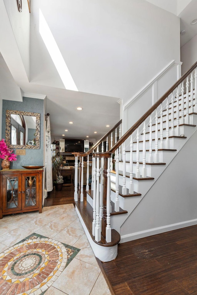 stairs with baseboards, a fireplace, wood finished floors, and a skylight
