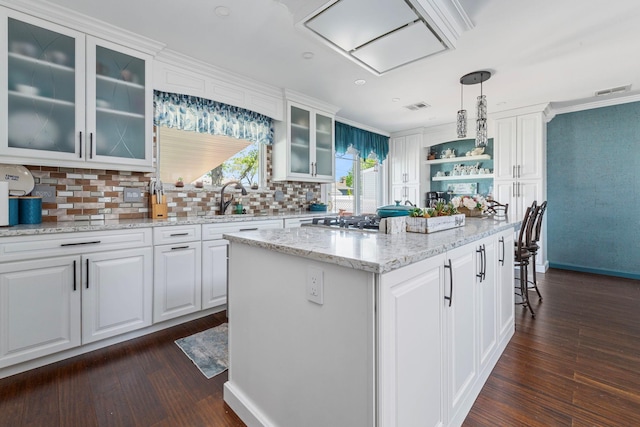 kitchen featuring visible vents, a center island, a sink, stainless steel gas stovetop, and dark wood-type flooring