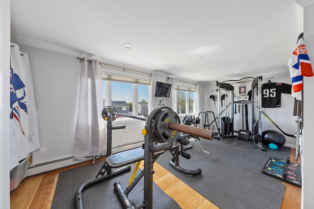 exercise area with crown molding, wood finished floors, and a baseboard radiator