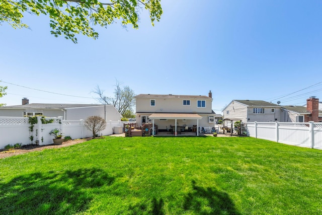 rear view of property with a fenced backyard, a yard, and a patio area