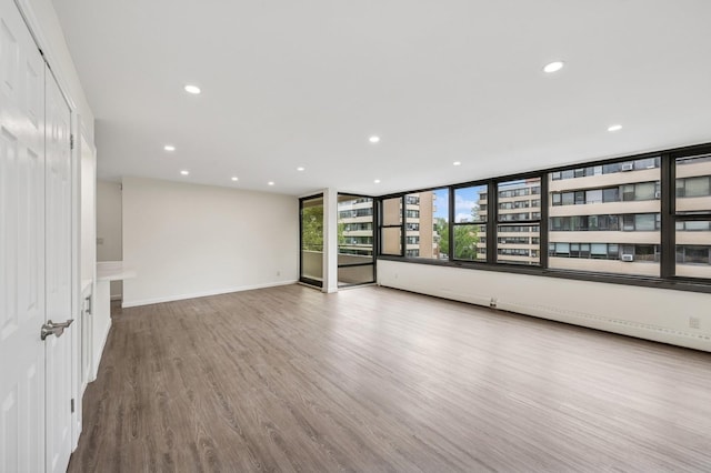 empty room featuring recessed lighting, wood finished floors, and baseboards