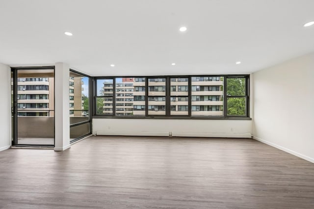 spare room with wood finished floors, baseboards, and recessed lighting