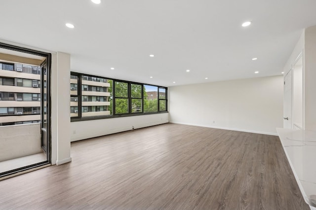 unfurnished living room featuring recessed lighting, wood finished floors, and baseboards