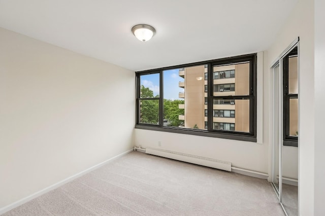 empty room featuring a baseboard radiator, carpet flooring, and baseboards