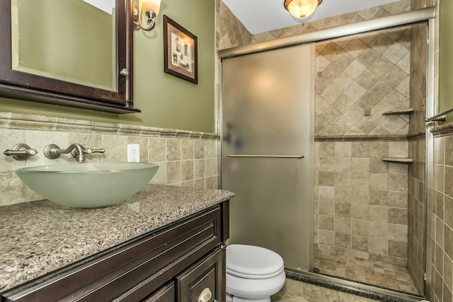 bathroom with vanity, a stall shower, toilet, and a wainscoted wall