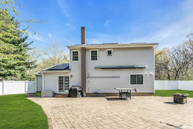 back of property featuring a patio, a gate, a chimney, and solar panels