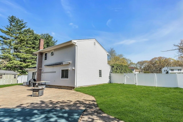 back of house with a lawn, a patio, a chimney, and a fenced backyard