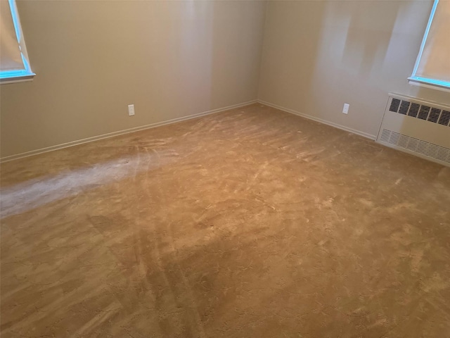 carpeted empty room with radiator heating unit and baseboards