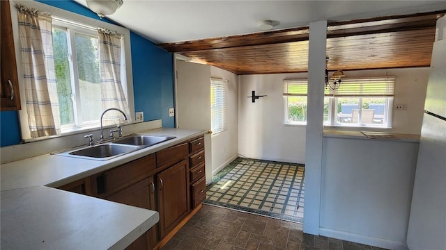 kitchen featuring light countertops, wooden ceiling, a sink, and freestanding refrigerator