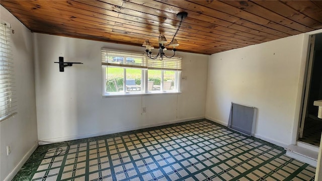 empty room featuring baseboards, wood ceiling, tile patterned floors, and a chandelier